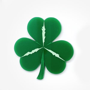 May include: A vibrant green shamrock with three heart-shaped leaves and a stem. The shamrock has a light green vein design in the center of each leaf. The image is set against a plain white background.