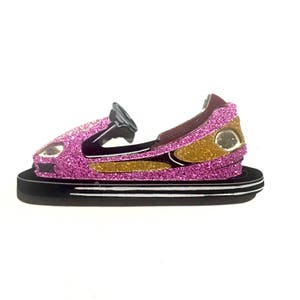 May include: A pink and gold glitter bumper car with a black base. Bumper cars are a popular attraction at amusement parks and carnivals.
