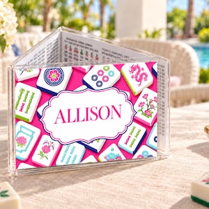 May include: A clear acrylic triangular Mahjong score card holder featuring a vibrant pink background with various Mahjong tile illustrations and a central white scalloped label containing the name ALLISON in bold pink capital letters.