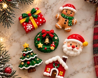 May include: A set of six Christmas-themed resin cabochons including a red gift box with a yellow ribbon, a gingerbread person with a green scarf, a green wreath with a gold bell, a Santa Claus face, a green Christmas tree, and a red house.