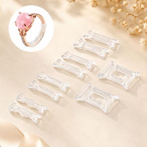 May include: A collection of clear, flexible ring size adjusters in various shapes and sizes, designed to wrap around a ring band. An inset shows a rose gold ring with a pink stone featuring one of these clear adjusters attached to the band.