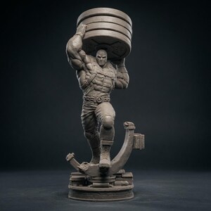 May include: A gray statue of a muscular figure wearing a mask and lifting a stack of weight plates overhead. The figure is posed on a circular base with a stylized support structure. The statue is detailed and appears to be made of a solid material.