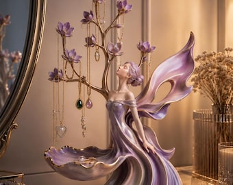 May include: A fairy-shaped jewellery holder with a flowing purple dress and large wings. The holder has a tree with purple flower accents for necklaces and a dish for rings. Gold accents are visible. The design is elegant and decorative.