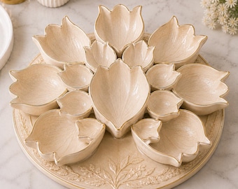 May include: A beige ceramic serving platter with multiple tulip-shaped bowls. The bowls are arranged in a circular pattern and have gold trim. The platter has a floral embossed design around the edge, ideal for serving snacks or appetizers.