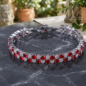 May include: A double-row tennis bracelet featuring alternating round-cut red gemstones and clear white stones set in a silver-toned metal frame. The bracelet is designed with a secure clasp mechanism and displays a consistent pattern of stones.