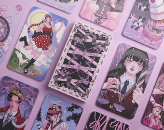May include: A collection of rectangular tarot cards featuring anime-style illustrations in shades of pink, purple, and black. The central card displays a black and white butterfly design with pink ribbons, while surrounding cards show various characters.
