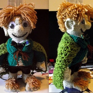May include: A crocheted doll with brown hair, a green cloak, and brown boots. The doll is wearing a green and brown shirt and a bow tie.