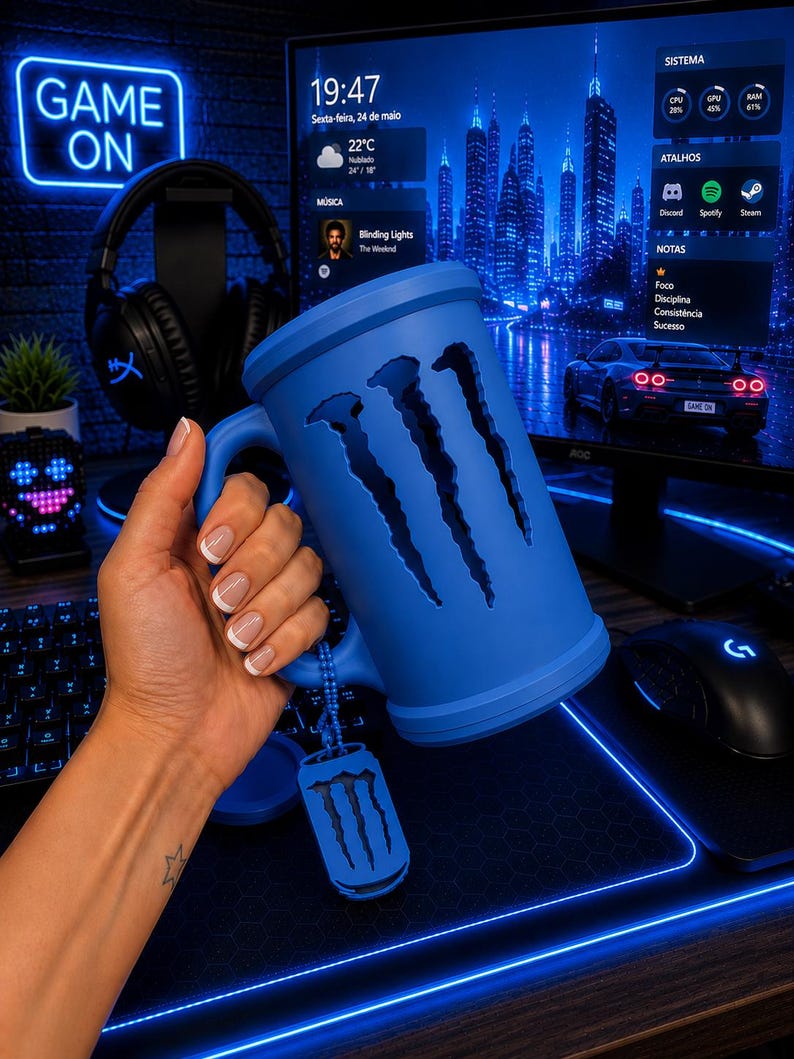 May include: A matte blue beer mug featuring the iconic three-claw scratch logo cut out on the side. The mug includes a matching blue dog tag style charm attached to the handle by a small ball chain, creating a cohesive look for a gaming setup.