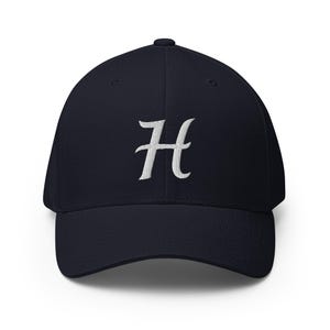 Op de afbeelding: Marineblauwe baseballcap met een gebogen klep. De cap heeft een wit geborduurd "H" op de voorkant. De hoed is gemaakt van een zacht, duurzaam materiaal en heeft een gestructureerde pasvorm.
