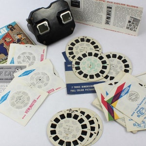 May include: A vintage View-Master viewer and a collection of reels featuring the cartoon character Top Cat. The reels are labeled "One View-Master Reel" and "Master Reel".