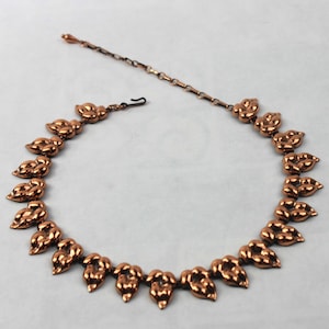 May include: A copper necklace with a chain and a design of connected teardrop shapes.