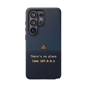 May include: A dark blue smartphone case featuring a small house graphic with lit windows against a starry night sky. Below the house, the text reads: There's no place like 127.0.0.1. The case has a cutout for a multi-lens camera system on the back.