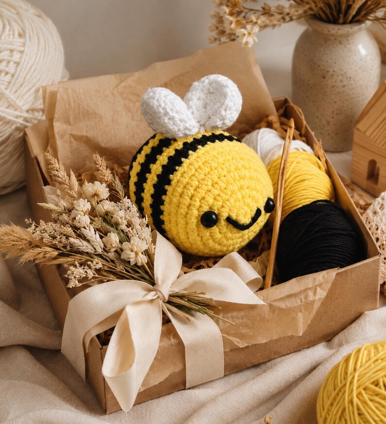 Peut inclure: Une abeille au crochet jaune et noir avec des ailes blanches dans une bo&icirc;te cadeau. La bo&icirc;te contient de la laine, un crochet et des fleurs s&eacute;ch&eacute;es. L'abeille a un visage souriant. La bo&icirc;te est attach&eacute;e avec un ruban cr&egrave;me.