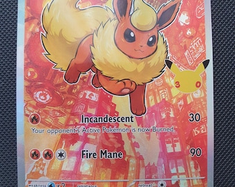 Puede incluir: Una carta coleccionable de Flareon con 110 HP, que presenta una ilustración roja y naranja de la criatura sobre un fondo urbano. La carta muestra los ataques Incandescent y Fire Mane, un logo del 25 aniversario y texto sobre 900 grados Celsius.