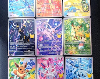 Puede incluir: Una colección de nueve cartas coleccionables rectangulares con coloridas ilustraciones de varias criaturas. Cada carta muestra un personaje único, nombres de ataques, valores de daño y un pequeño logo dorado de aniversario.