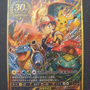 May include: A gold-bordered Pokemon trading card featuring Ash Ketchum, Pikachu, Charizard, Blastoise, and Venusaur. The card displays a 30th Anniversary logo, 300 HP, and Japanese text including the title Satoshi no Nakamatachi.