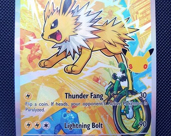 Puede incluir: Una carta coleccionable holográfica de Jolteon que muestra a la criatura eléctrica amarilla con un cuello blanco, una bicicleta verde y un icono de silueta de Pikachu. La carta muestra 100 HP, ataques Thunder Fang y Lightning Bolt.