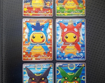 Puede incluir: Seis tarjetas coleccionables rectangulares que muestran a Pikachu vestido con varios disfraces temáticos de Pokémon. Cada tarjeta presenta texto en japonés, valores numéricos y fondos holográficos coloridos con patrones de estrellas y círculos.
