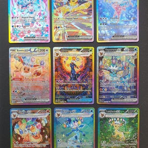 Puede incluir: Una colección de nueve cartas coleccionables Pokemon holográficas dispuestas en una cuadrícula de tres por tres. Cada carta muestra un personaje diferente de la evolución de Eevee con ilustraciones coloridas, ataques y valores numéricos.