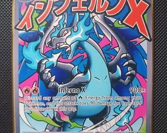 Puede incluir: Una carta coleccionable Mega Charizard X EX con 10000 HP, que muestra una criatura azul similar a un dragón con llamas, texto en japonés y el ataque Inferno X. La carta tiene un fondo colorido con remolinos rosas y azules y un borde dorado.
