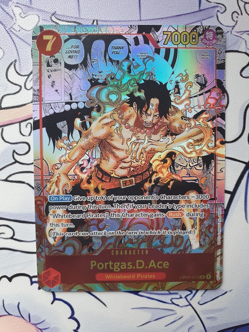 May include: A holographic trading card featuring the character Portgas D. Ace from the "Whitebeard Pirates" series. The card has a red and gold color scheme, with the number 7 in the upper left corner and the character's name at the bottom.