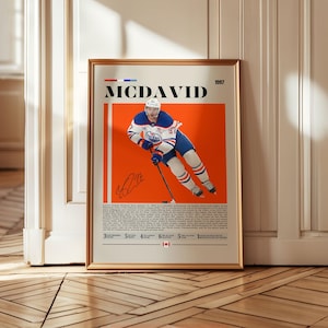 May include: Framed poster featuring Connor McDavid in an Edmonton Oilers uniform against an orange background. The poster includes the name "MCDAVID" and the year "1997" at the top, with a signature and statistics at the bottom.