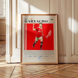 Könnte beinhalten: Gerahmtes Poster mit goldenem Rahmen, das einen Fußballspieler in einem roten Trikot zeigt. Das Poster hat den Namen "GARNACHO" oben, einen roten Hintergrund, das Bild des Spielers und eine Unterschrift.