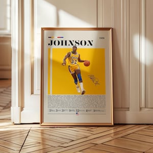 May include: A framed poster featuring basketball player Magic Johnson in a yellow and gold Lakers uniform, dribbling a basketball. The poster includes the name "JOHNSON" in bold letters, a signature, and text at the bottom.