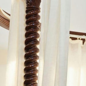 Detail of hand-carved spiral wooden pillars on a solid teak four-poster canopy bed inspired by classic Italian furniture.