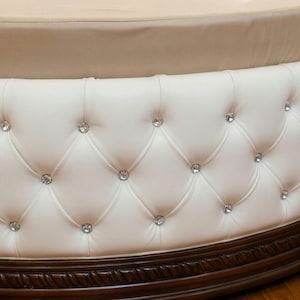 White button-tufted circular base of a bespoke luxury round bed frame, showcasing premium upholstery and solid wood trim.