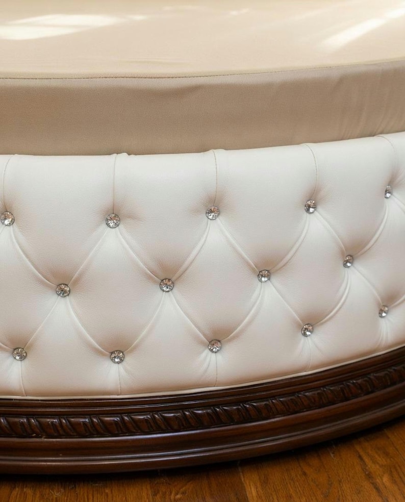 White button-tufted circular base of a bespoke luxury round bed frame, showcasing premium upholstery and solid wood trim.