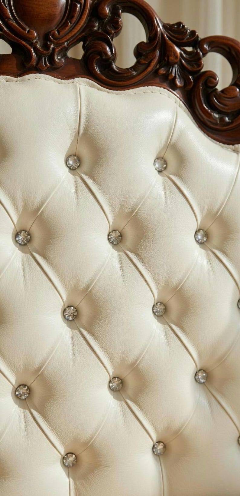 May include: Close-up of a cream-colored, tufted headboard with diamond stitching and crystal-like button accents. The headboard has a dark brown, ornate wooden frame.