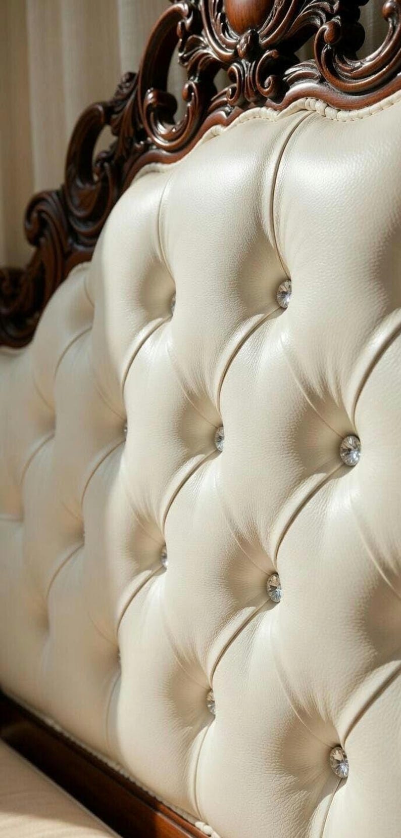 May include: Close-up of a cream-colored, tufted headboard with diamond-shaped crystal accents. The headboard has a dark brown, ornate wooden frame. The design is classic and elegant, suitable for a bedroom.
