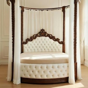Puede incluir: Una cama redonda con dosel, con estructura de madera oscura y cabecero y base acolchados en blanco roto. La cama tiene un dosel con cortinas blancas transparentes. La cama está sobre un suelo de madera.