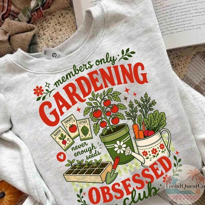 Puede incluir: Una sudadera gris claro con tem&aacute;tica de jardiner&iacute;a. El dise&ntilde;o incluye las palabras "members only GARDENING OBSESSED club" en rojo y verde, junto con ilustraciones de verduras, sobres de semillas y herramientas de jardiner&iacute;a.