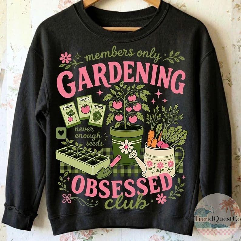 Puede incluir: Sudadera negra con un dise&ntilde;o de jardiner&iacute;a. El dise&ntilde;o incluye las palabras "GARDENING OBSESSED CLUB" en rosa y verde, junto con ilustraciones de verduras, paquetes de semillas y herramientas de jardiner&iacute;a. Tambi&eacute;n se incluye el texto "members only".