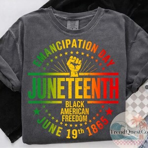 May include: Dark gray sweatshirt with a colorful Juneteenth graphic. The design includes the words "Emancipation Day" and "Juneteenth" in green, yellow, and red, along with the text "Black American Freedom June 19th 1865". A raised fist is in the center.