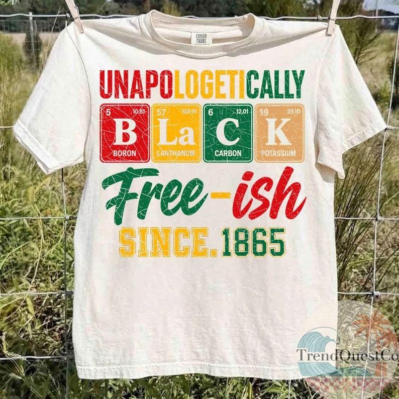 May include: Off-white t-shirt with the words "UNAPOLOGETICALLY BLACK" in red, yellow, and green, with the word "BLACK" spelled out using periodic table elements. Below, the shirt reads "Free-ish SINCE 1865".