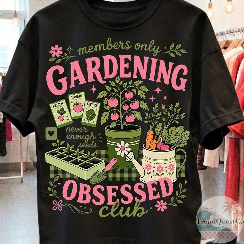 Puede incluir: Camiseta negra con un dise&ntilde;o de jardiner&iacute;a. El dise&ntilde;o incluye las palabras "members only GARDENING OBSESSED club" en rosa, junto con ilustraciones de plantas, semillas y herramientas de jardiner&iacute;a. La camiseta tiene cuello redondo y mangas cortas.