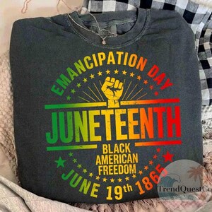 May include: Dark gray crew neck sweatshirt with a colorful Juneteenth graphic. The design includes the words "Emancipation Day" and "Juneteenth" in a vibrant, multi-colored font, along with the text "Black American Freedom" and "June 19th 1865".