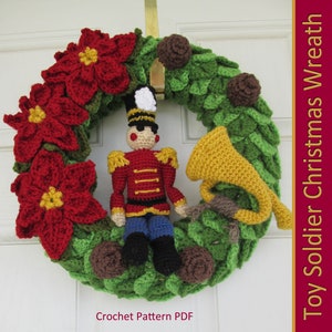 May include: A crocheted Christmas wreath featuring a toy soldier holding a trumpet, poinsettia flowers, and pine cones. The wreath is green and red with a brown background. Crochet Pattern PDF.