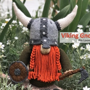 May include: A knitted Viking gnome with a grey helmet, orange beard, and cream horns. The gnome is holding a shield and an axe. The text "Viking Gnome Pin Loom Pattern" is displayed on the image.