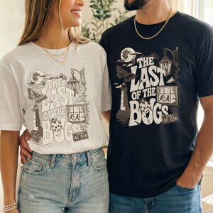 Puede incluir: Una camiseta blanca y una camiseta negra, cada una con un estampado gr&aacute;fico con el texto THE LAST OF THE BUGS. El dise&ntilde;o incluye un faro, una polilla, una mariquita, un farol y un marco de ventana con siluetas, todo en estilo monocrom&aacute;tico.