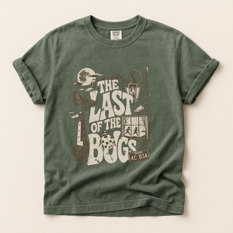 Puede incluir: Una camiseta de manga corta color verde salvia con un estampado gr&aacute;fico marr&oacute;n que incluye el texto THE LAST OF THE BUGS. El dise&ntilde;o muestra un faro, una polilla, una mariquita, un farol, una ventana con dos figuras y una matr&iacute;cula 4C B3A.