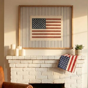 Puede incluir: Una pieza de arte mural rectangular que presenta un gr&aacute;fico de la bandera estadounidense centrado sobre un fondo de rayas verticales negras, enmarcado en madera clara. Un textil con la bandera de EE. UU. cuelga sobre la repisa de ladrillo blanco.