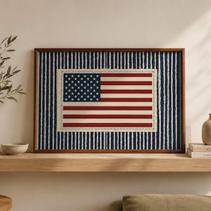 May include: Framed print of the American flag. The flag features red and white stripes and a blue canton with white stars. The flag is set against a blue and white striped background, framed in a brown wooden frame.