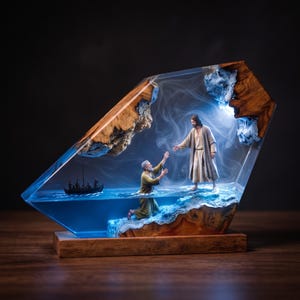 May include: A decorative resin and wood sculpture depicting a scene of a figure reaching out to another standing on water. The piece features natural wood edges, a translucent blue resin centre, and internal lighting with wispy smoke effects.