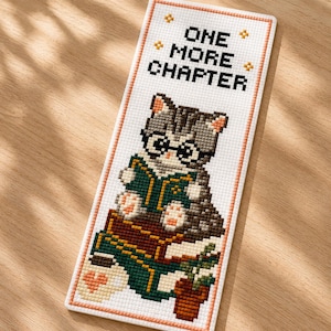May include: A cross-stitch bookmark featuring a gray tabby cat wearing glasses and reading a book. The bookmark has the text "ONE MORE CHAPTER" at the top, with decorative star accents. The cat is reading a green book with a brown cover.