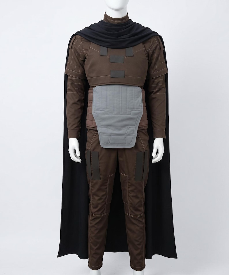 May include: A brown long-sleeved shirt and matching trousers set featuring a grey abdominal plate, dark brown rectangular shoulder and leg patches, and a black cape draped over the shoulders with a high collar, displayed on a white mannequin.