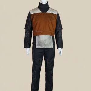 May include: A full costume displayed on a mannequin. The outfit includes a black turtleneck, black trousers, and a brown and grey vest. White stitching accents the black fabric. The vest has a quilted design on the shoulders.